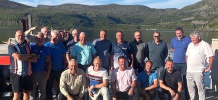 En gruppe glade sportsfiskere poserer på kaien etter en vellykket fisketur til Norge